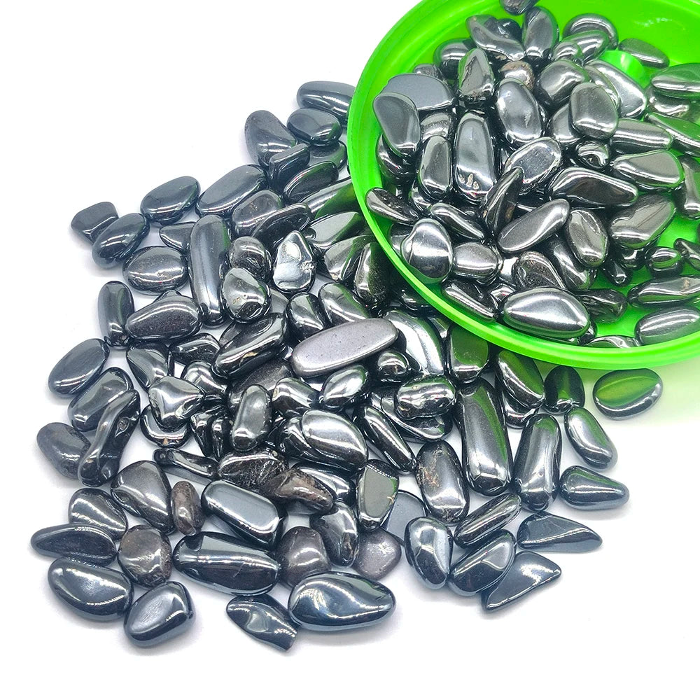 A pile of tumbled natural crystal stone chips in various shades of gray and black, with a green bowl nearby.