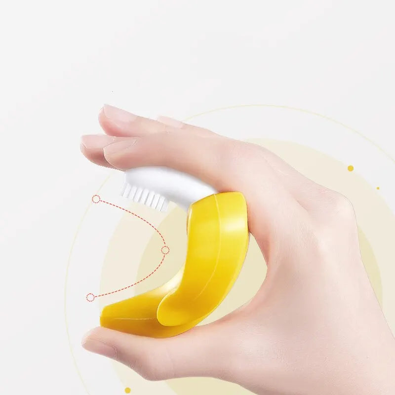 A hand holds a yellow silicone baby teether and training toothbrush, showing the product's shape and size.