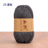 A skein of dark gray cotton blend crochet yarn is shown on a wooden surface.