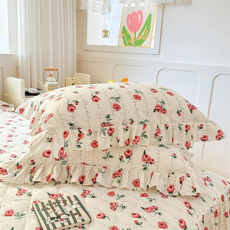 A set of two floral cotton pillowcases featuring pink roses on a cream background.