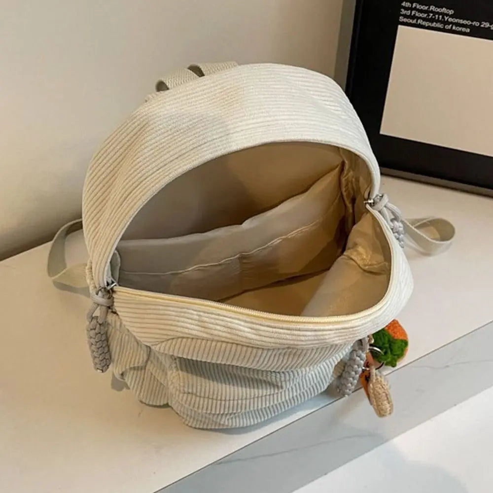 A light beige corduroy casual backpack is shown open, displaying its interior lining and strap details.