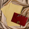 A stack of yellow lined paper and a red envelope with a gold sealing wax sticker on a silky fabric background.