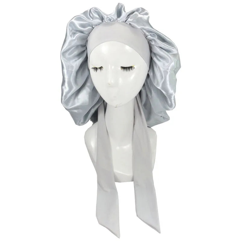 A white satin sleep cap with a voluminous silver fabric drape is displayed on a mannequin.