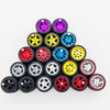 A collection of ten 1:64 scale alloy car wheels and tires in various colors including black, yellow, red, and blue.