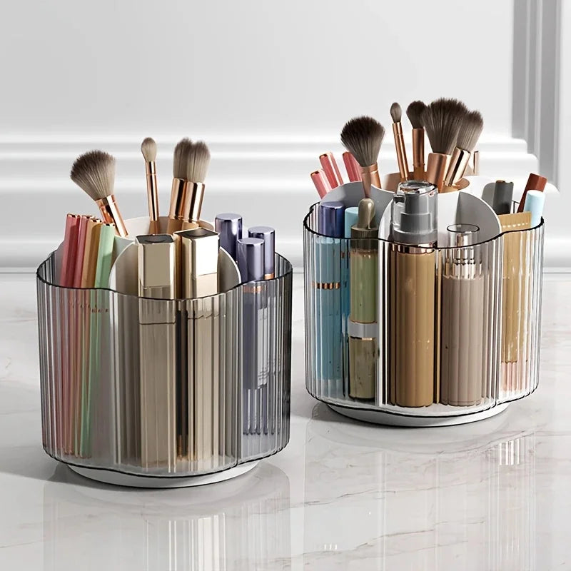 A clear rotating makeup brush holder with six compartments filled with various makeup brushes and tools.
