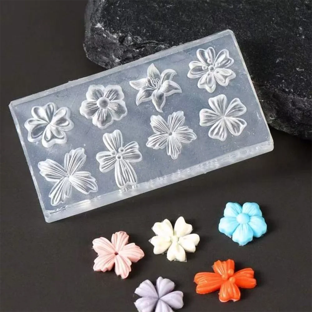 Clear silicone molds of various flower shapes for nail art, displayed on a dark surface.