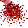 A pile of shiny holographic star sequins in various shades of red and pink scattered on a white background.