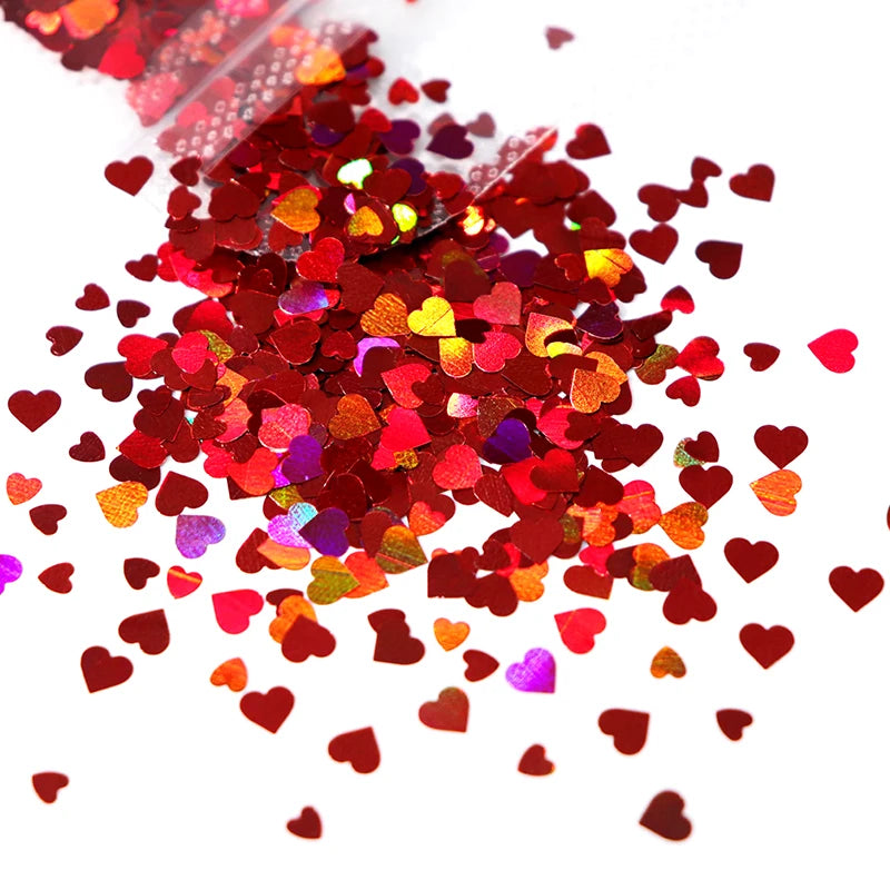 A pile of shiny holographic star sequins in various shades of red and pink scattered on a white background.