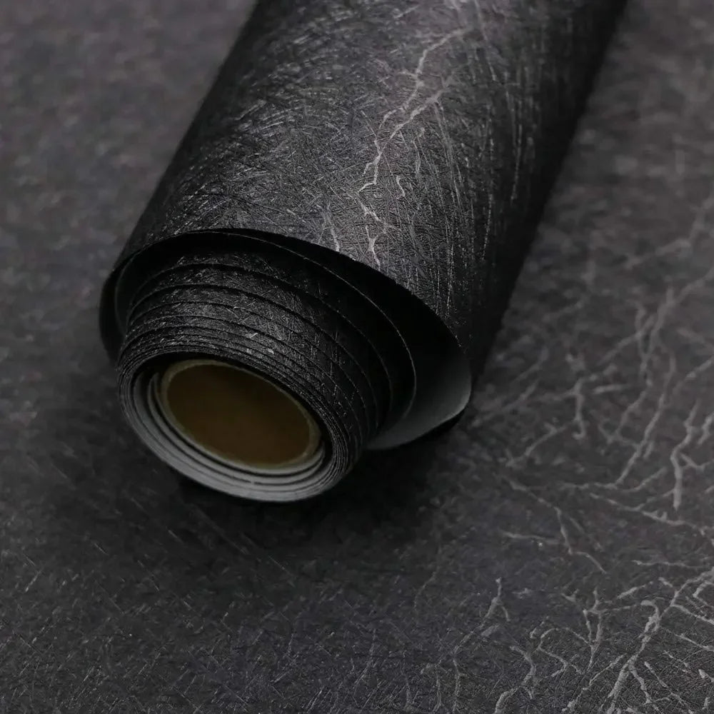 Roll of black embossed silk self-adhesive wallpaper being unrolled