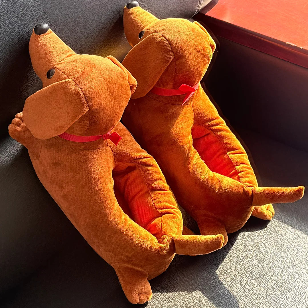A pair of brown plush cartoon dog slippers with red accents resting in a dark box.