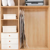 A wooden storage cabinet with shelves holding white storage boxes and a hanging compression bag.