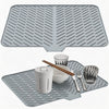 A silicone dish drying mat with a drainage ramp is shown, featuring a textured surface and holding a cup, utensils, and a gla
