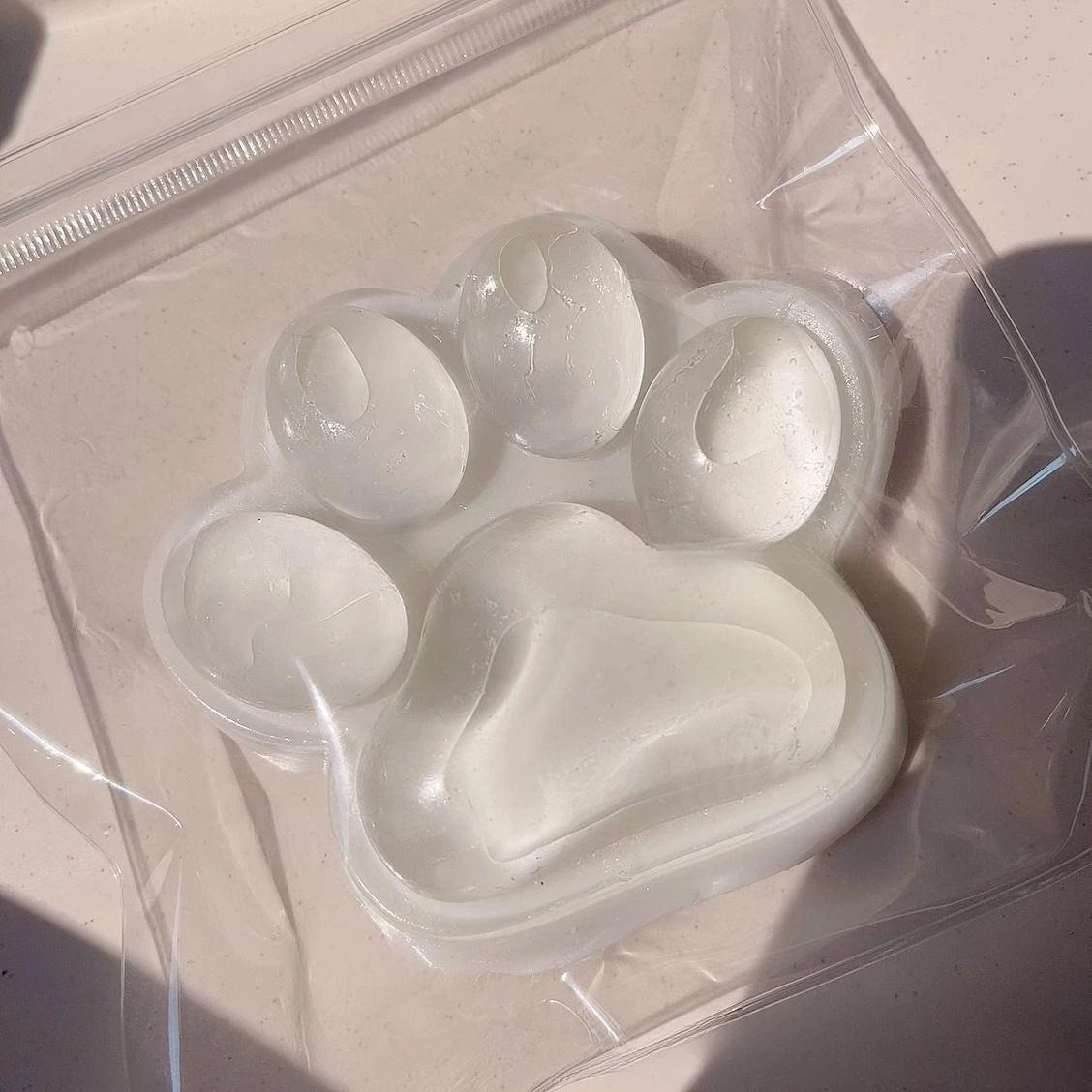 A clear plastic bag contains a silicone cat paw squeeze toy for stress relief and fidgeting.