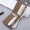 A brown PU leather wallet with multiple card slots and a coin pocket resting on a laptop keyboard.