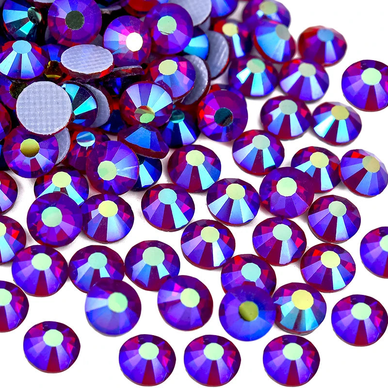 A close-up view of various iridescent purple and blue rhinestones scattered on a white background.