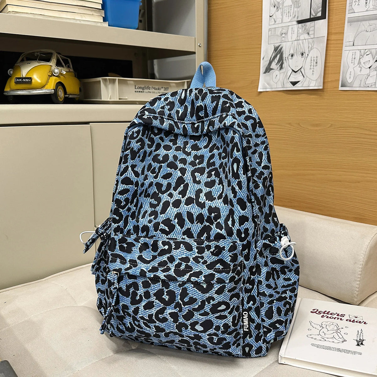 A blue and black leopard print nylon backpack with multiple pockets resting on a light surface.