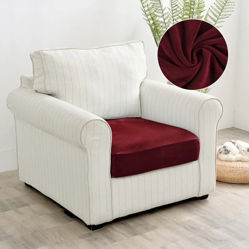 A cream upholstered armchair with a deep burgundy velvet seat cover and a decorative wreath in the background.