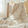 Flauschiges weißes Kunstpelz-Kaninchen-Fleece-Decke auf einer Oberfläche am Fenster.