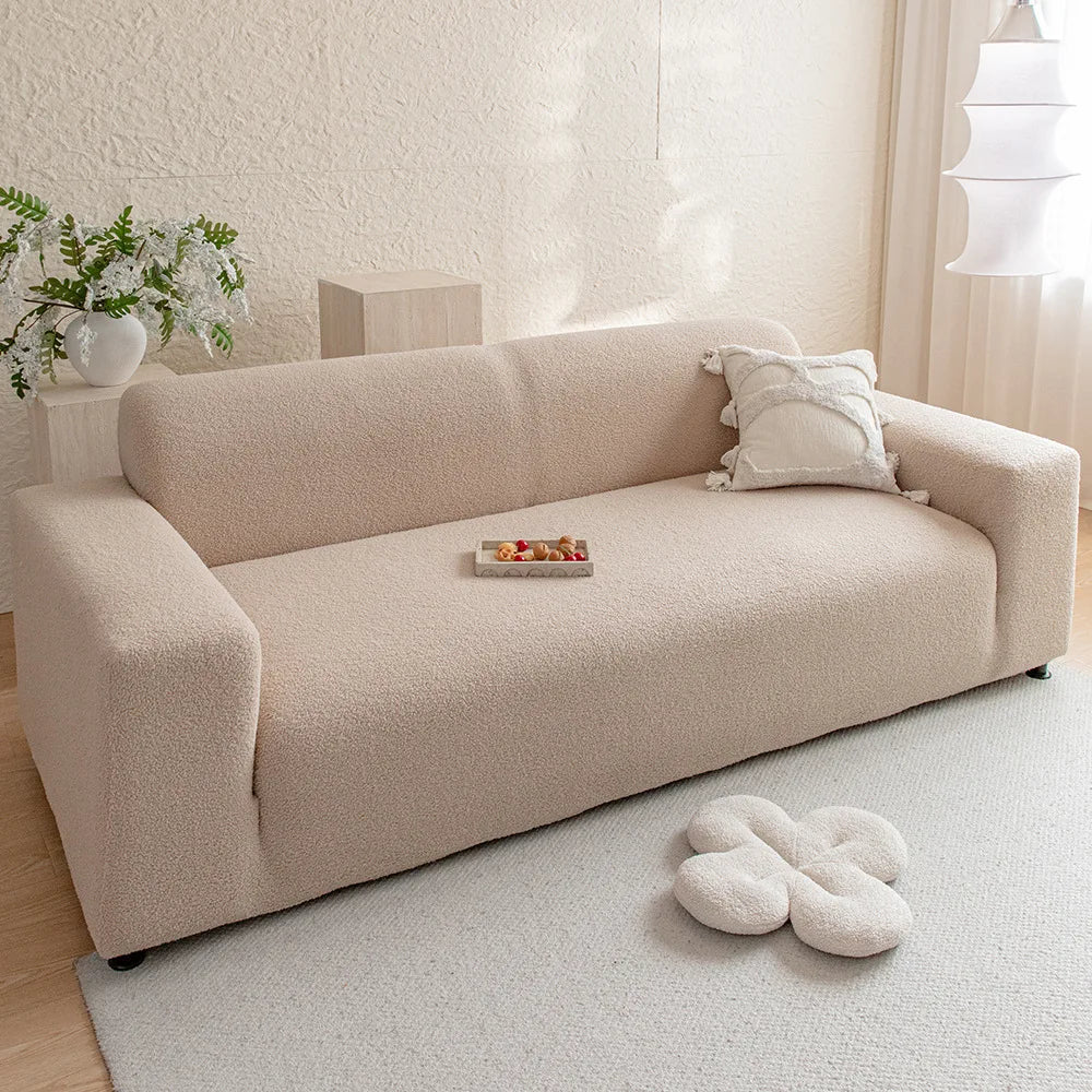 A beige plush sofa cover with a light-colored rug and decorative pillows in a bright room.