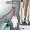 A rustic wooden wall-mounted towel clip hanging on a gray tiled wall next to a white towel and a toilet.