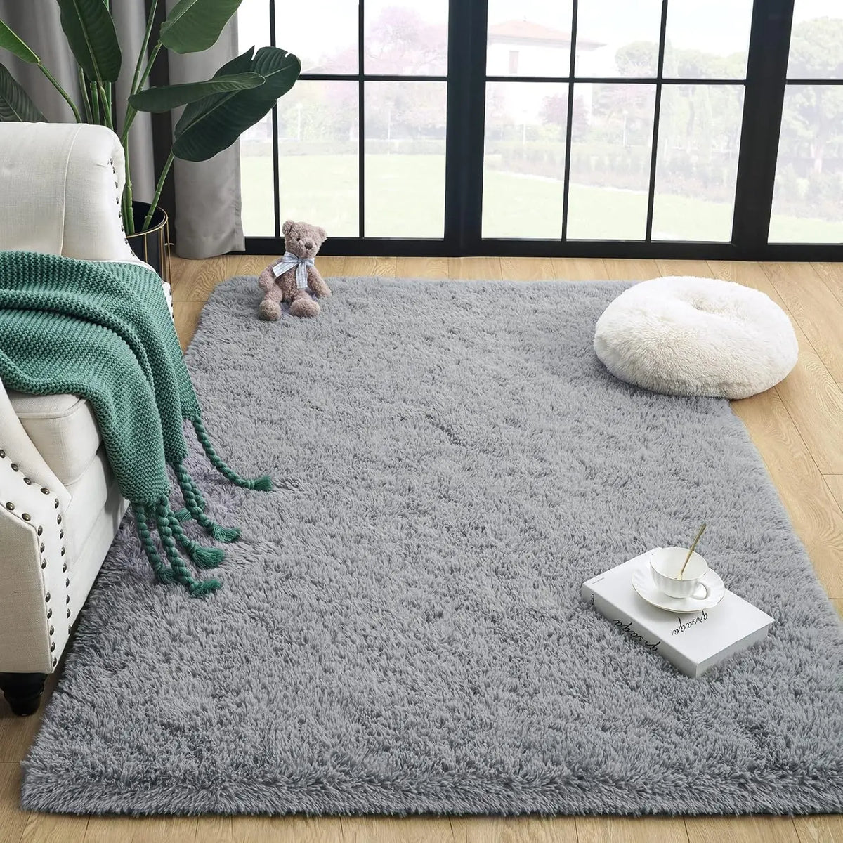 Grauer, tiegedyedter Teppich wird in einem Raum mit weißer Couch, grünem Strickwurf und Teddybär gezeigt.