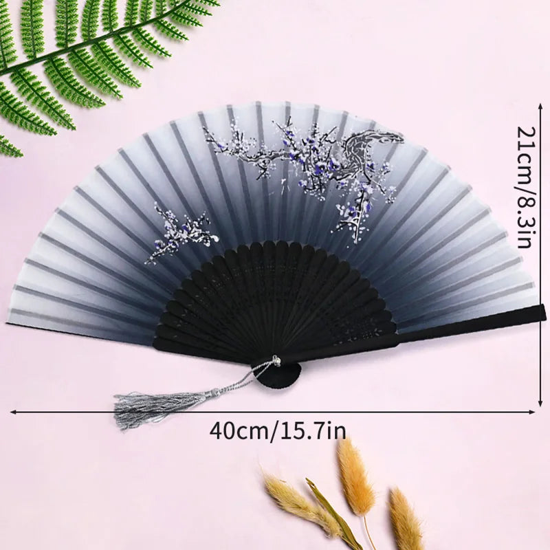 A black and silver vintage lace folding hand fan with a durable handle displayed against a pink background.