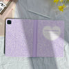 A purple composition notebook and pencil holder case for an iPad is shown on a light green fabric.
