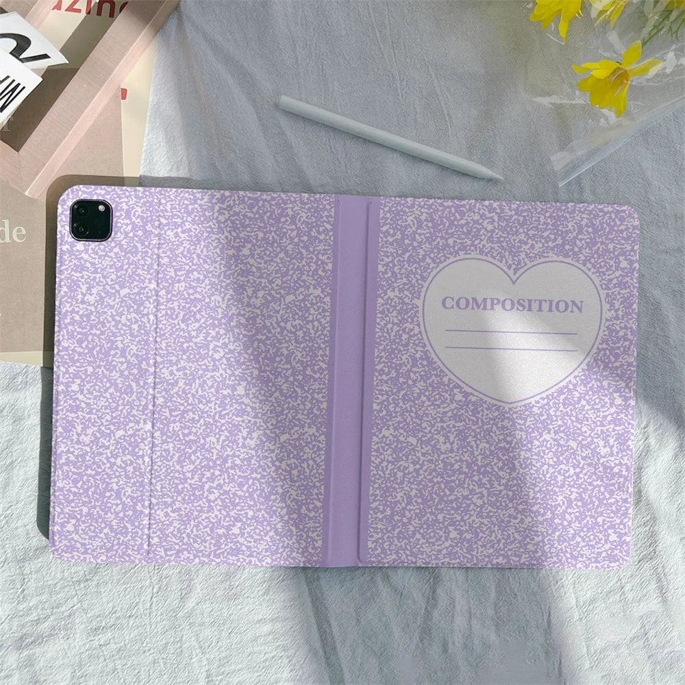 A purple composition notebook and pencil holder case for an iPad is shown on a light green fabric.