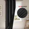 A black blackout curtain is installed on a window, showing its drape and mounting hardware.