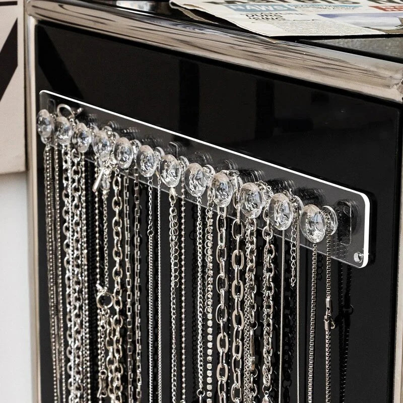 Wall-mounted acrylic jewelry organizer featuring crystal knobs and silver chains.