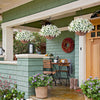 Artificial hanging morning glory flowers in white bloom baskets displayed on a porch