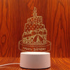A laser-cut silhouette of a birthday cake with candles and the words HAPPY BIRTHDAY on a light wood background.