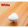 A white heart-shaped toilet flush button resting on a wooden surface.