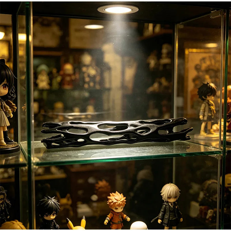 A black willow wood wishing stick displayed in a glass cabinet with various collectible figures.
