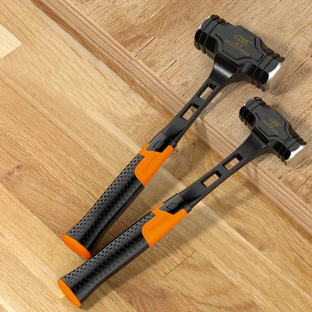 A black octagonal bush hammer with an orange anti-slip handle resting on a wooden surface.
