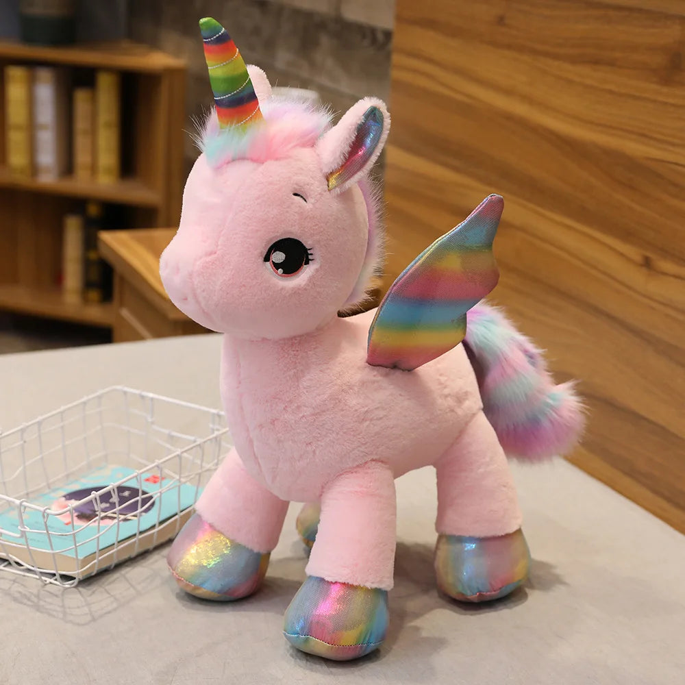 A pink unicorn plush toy with rainbow accents and glitter feet standing on a light surface.
