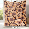 A tan flannel throw blanket featuring a repeating pattern of cartoon capybara faces in brown and orange tones.