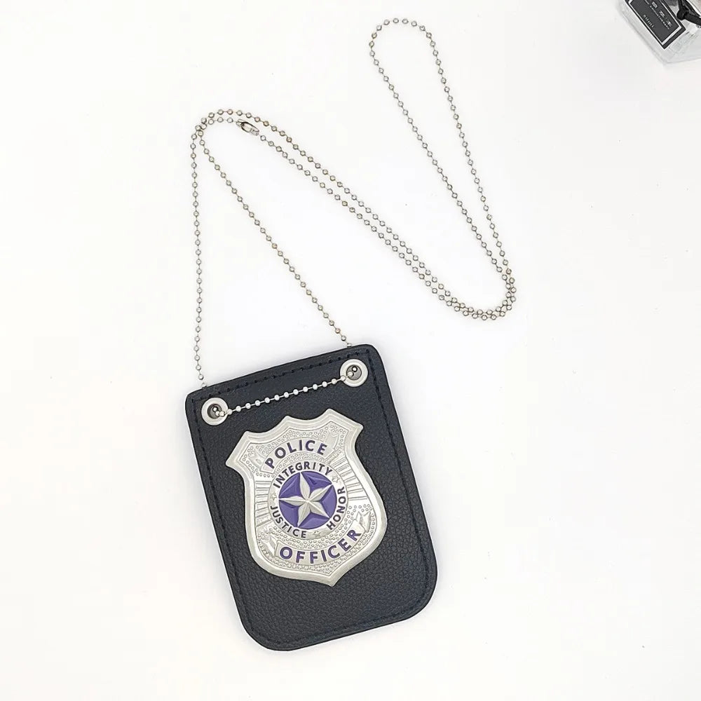 A dark gray police badge accessory featuring a shield design, surrounded by a silver chain and clip.