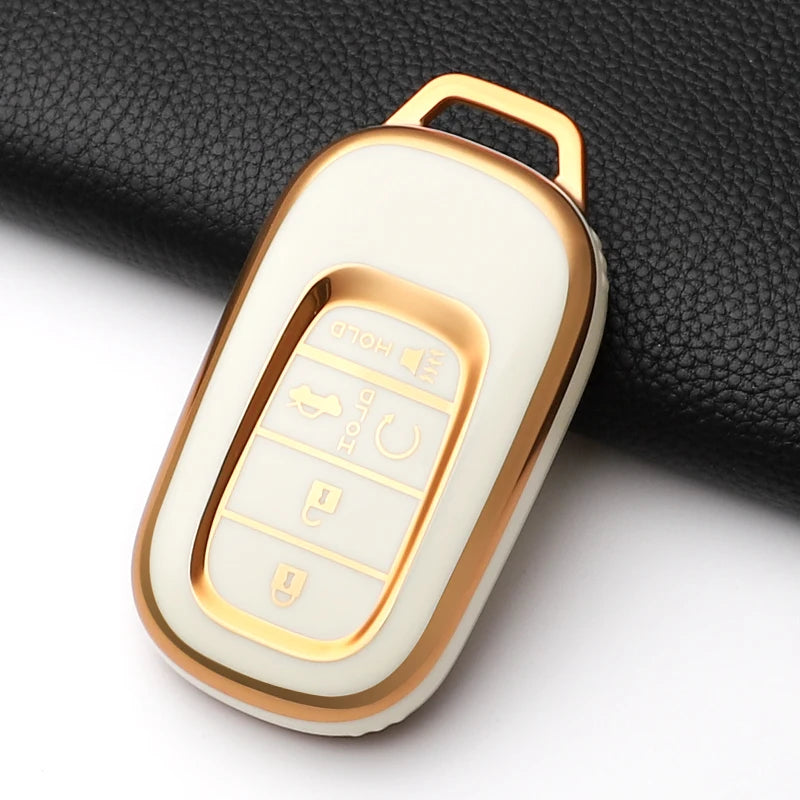 A white and gold anti-scratch TPU protective case for a Honda key fob, shown against a black fabric background.