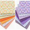 A bundle of colorful cotton fabric squares featuring floral dot patterns in yellow, orange, purple, and white.