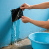 Hände tragen wasserdichte Dichtband auf eine blaue Wand, während Wasser heruntertropft.