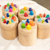 A wooden color sorting toy for toddlers featuring various colored stacking blocks arranged in circular patterns.