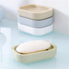 A stack of beige and light blue compact travel soap holders, with one holder lying open on a light blue surface.