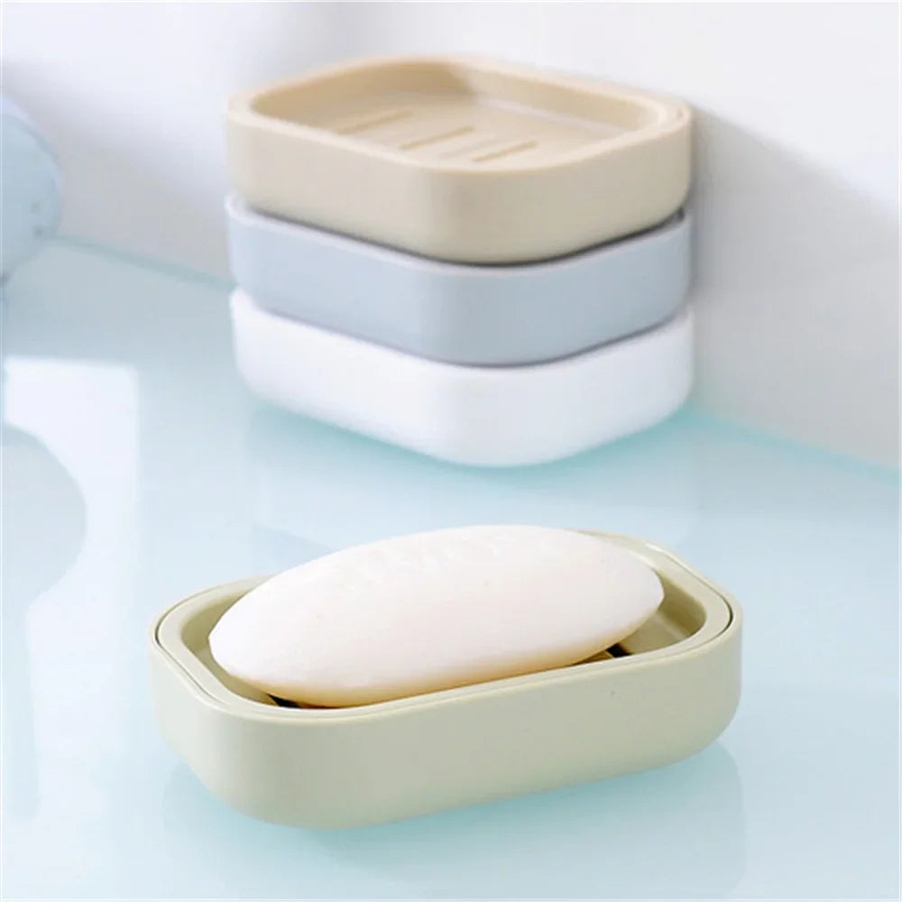 A stack of beige and light blue compact travel soap holders, with one holder lying open on a light blue surface.