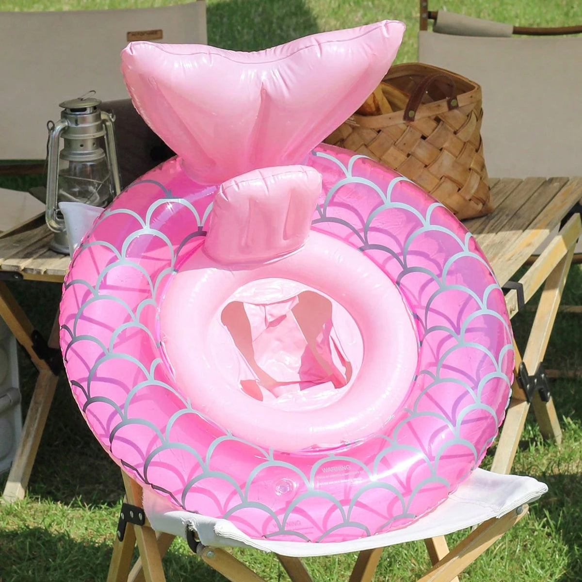 Pink inflatable swim ring with a scale pattern resting on a wooden table.