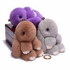 A set of fluffy angel bunny keychains in purple and gray with pom pom tails