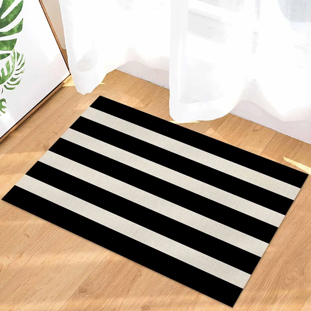 A rectangular black and white striped non-slip door mat lying on a wooden floor.