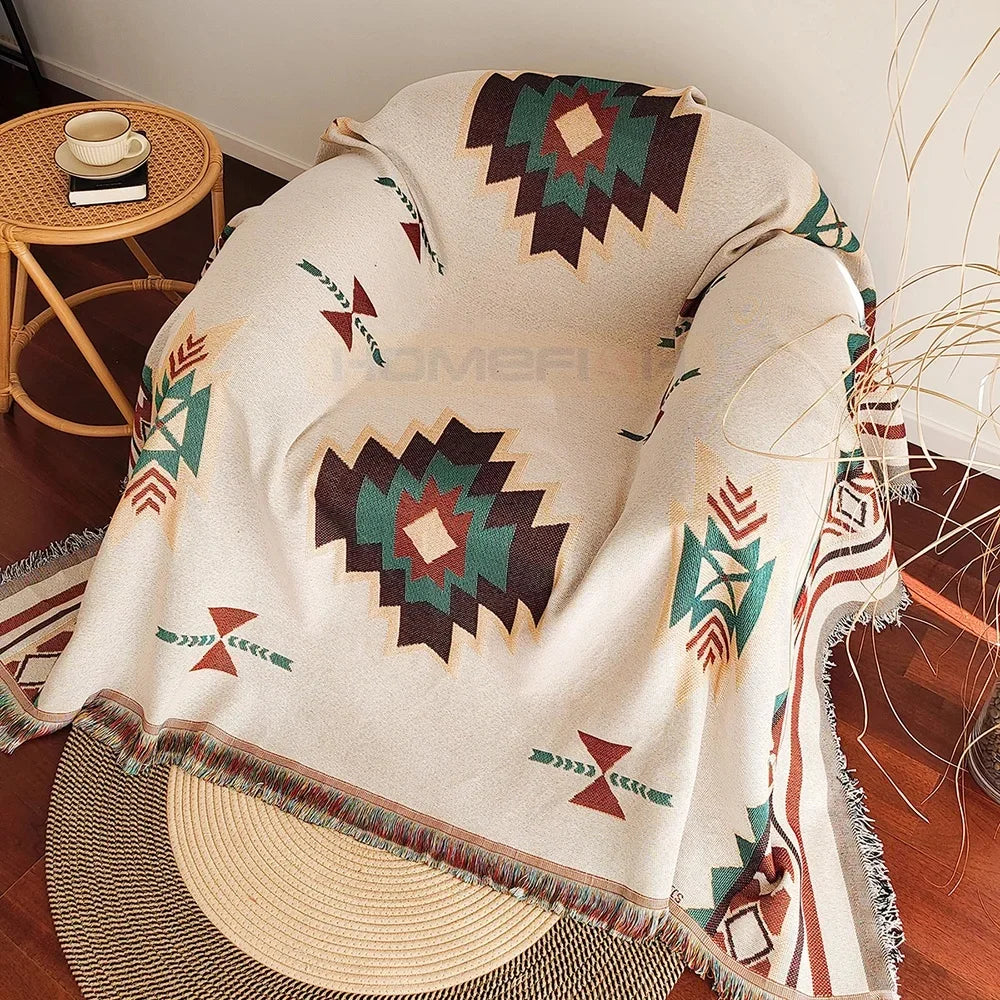 Oversized Aztec boho throw blanket in beige and brown with fringe draped over a wooden chair.