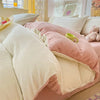 A close-up of a cozy milk velvet bedding set featuring a pink duvet cover and white pillows.