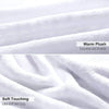 Close-up of a white plush fleece throw blanket showing soft texture and folds.